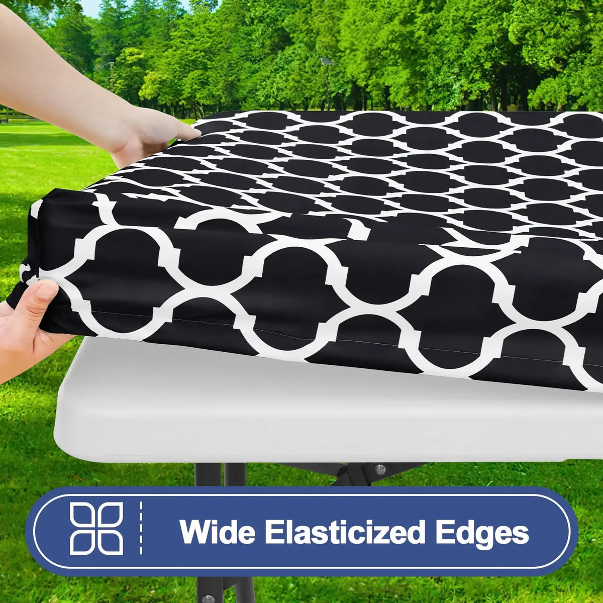 Black and white geometric patterned waterproof elastic fitted tablecloth being held over a white table.
