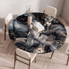 A round table set for dining featuring a dark blue and gold marble print tablecloth on a wooden table.