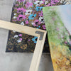 A wooden easel holds a canvas art poster featuring vibrant floral and abstract colors.