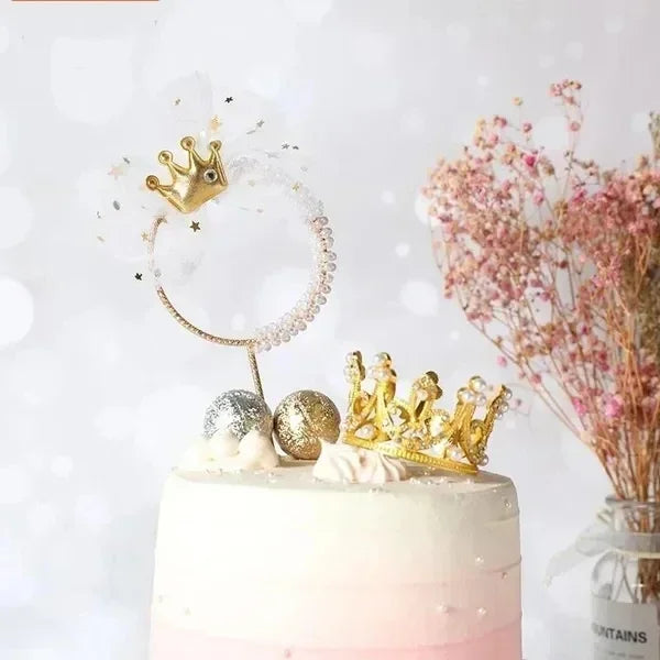 A white cake decorated with gold and silver crown toppers and delicate floral accents.