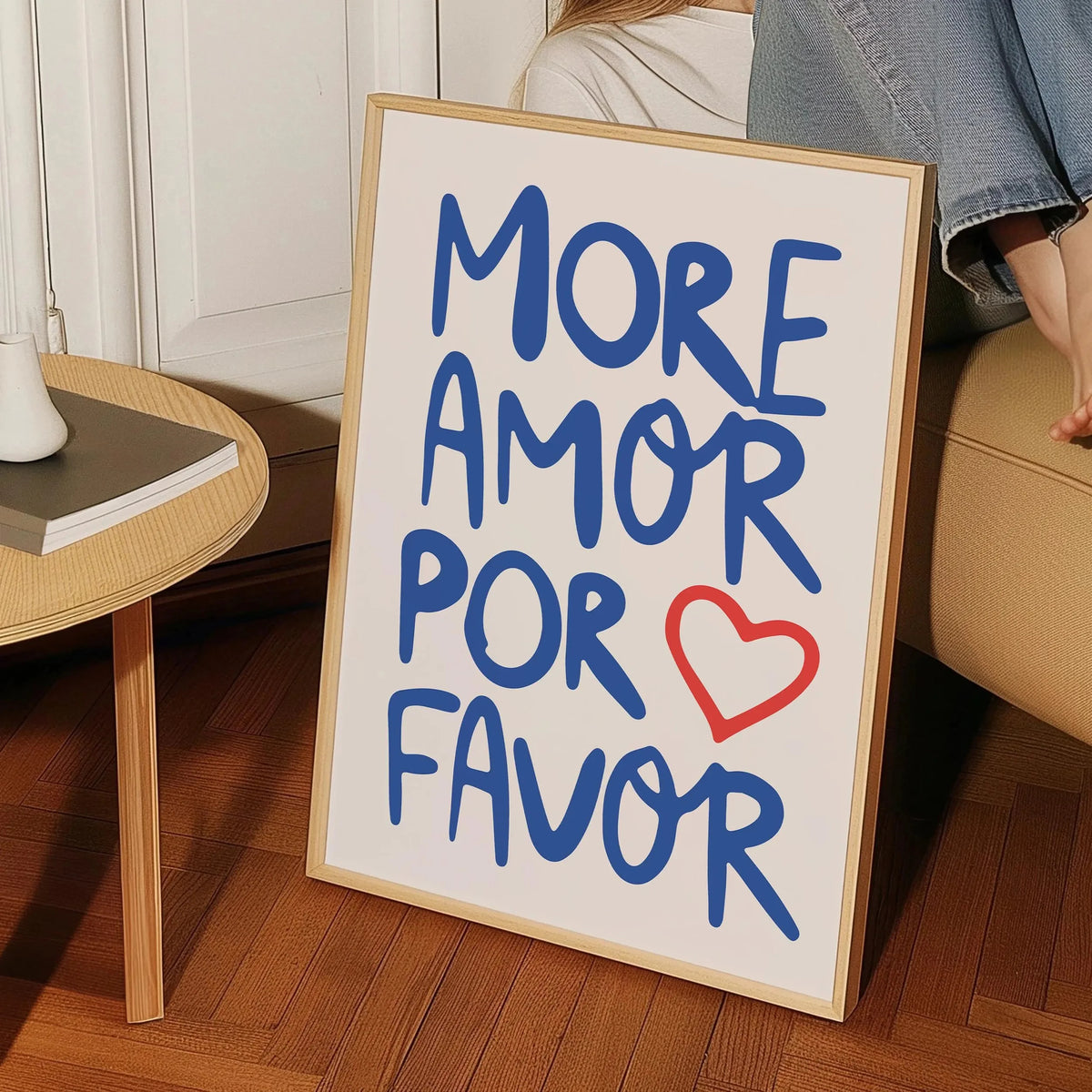 A framed canvas print featuring the text MORE AMOR FOR FAVOR in blue script on a light background.