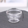 Clear glass miniature dollhouse vase and wine bottle set resting on a dark surface.