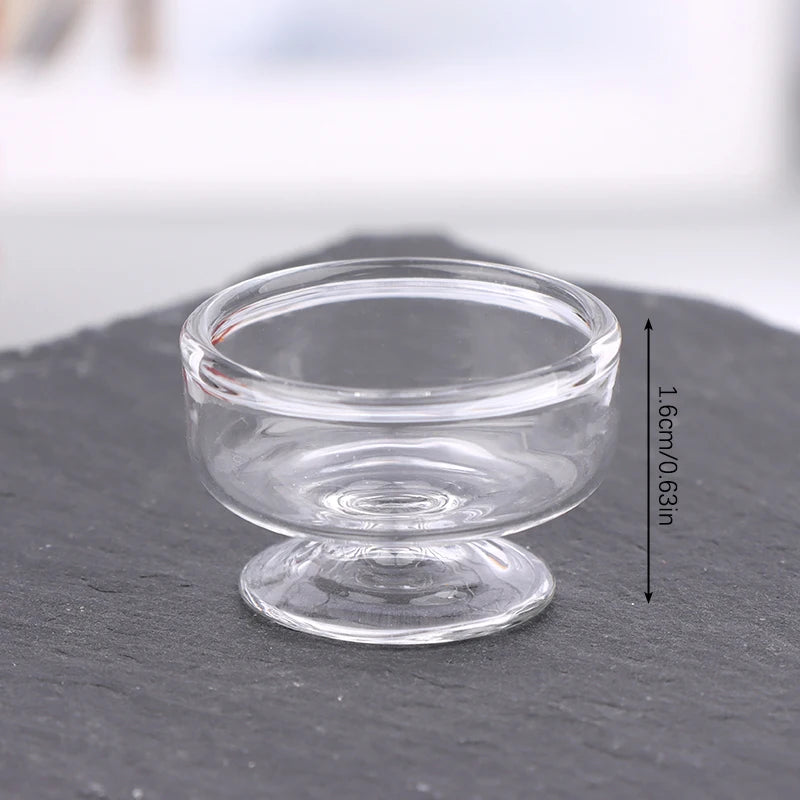 Clear glass miniature dollhouse vase and wine bottle set resting on a dark surface.