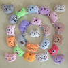 A collection of small, soft plush dolls shaped like various cats in pastel colors and textures.
