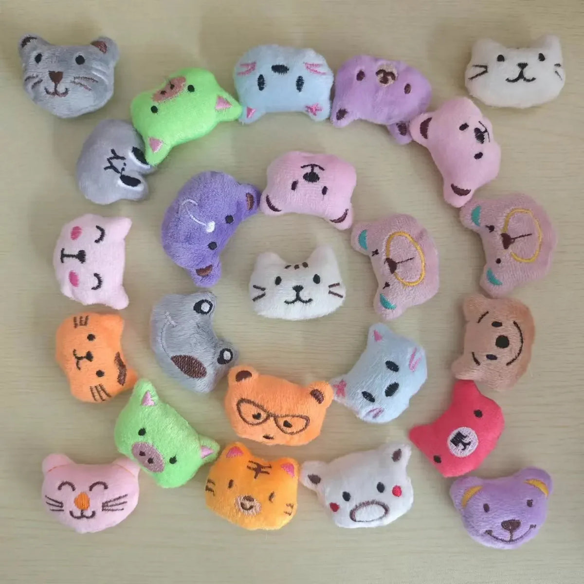 A collection of small, soft plush dolls shaped like various cats in pastel colors and textures.