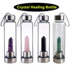 Cinco botellas de vidrio con cristales de varios colores usados para agua curativa