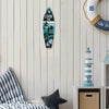 A black wooden surfboard sign with palm trees and the text Live the Dream hanging on a white wall.