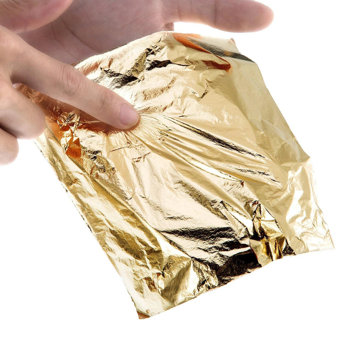 A hand is holding a sheet of imitation gold leaf for crafting or gilding.
