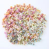 A dense arrangement of silk artificial flower heads in soft pink, peach, and pale green tones.