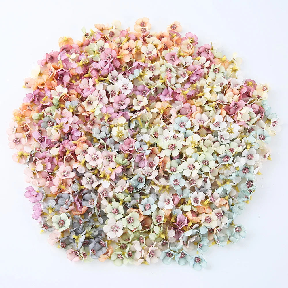 A dense arrangement of silk artificial flower heads in soft pink, peach, and pale green tones.