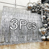 Silver metallic fringe curtains used as a backdrop for a party decoration featuring a cluster of silver balloons.