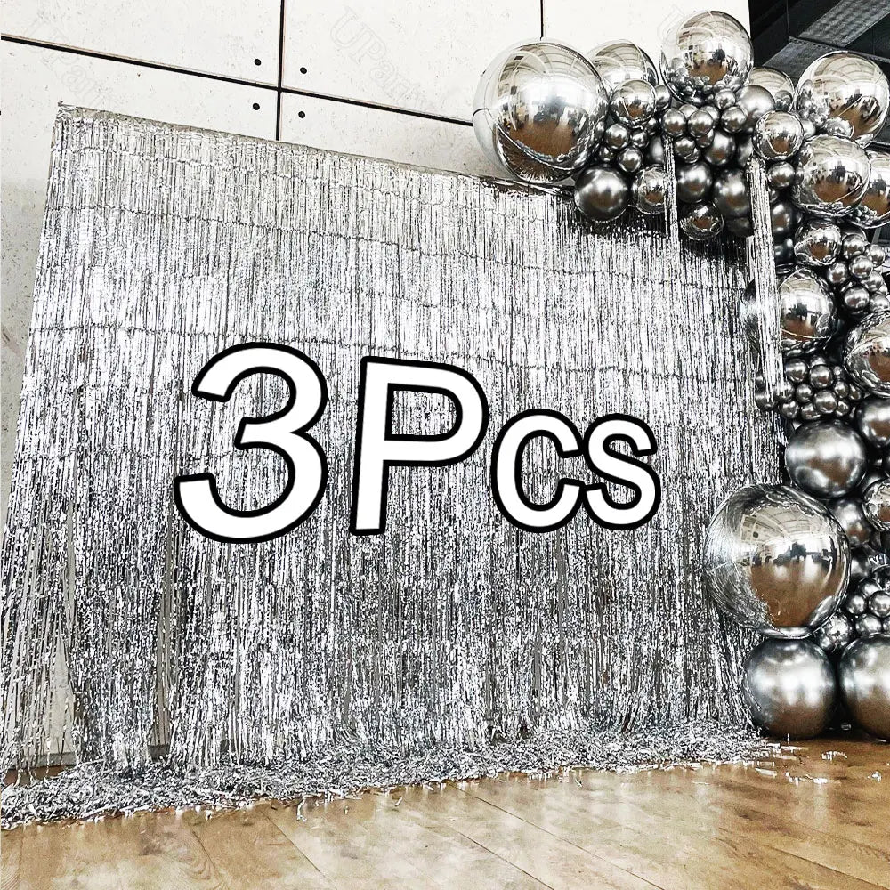 Silver metallic foil fringe curtains used as a backdrop for party decor featuring a cluster of silver balloons.