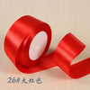 A roll of bright red silk satin ribbon used for gift wrapping and craft projects.