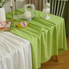 A lime green rectangular tablecloth set for dining or events, featuring white ceramic decor and a vintage-style wooden chair.