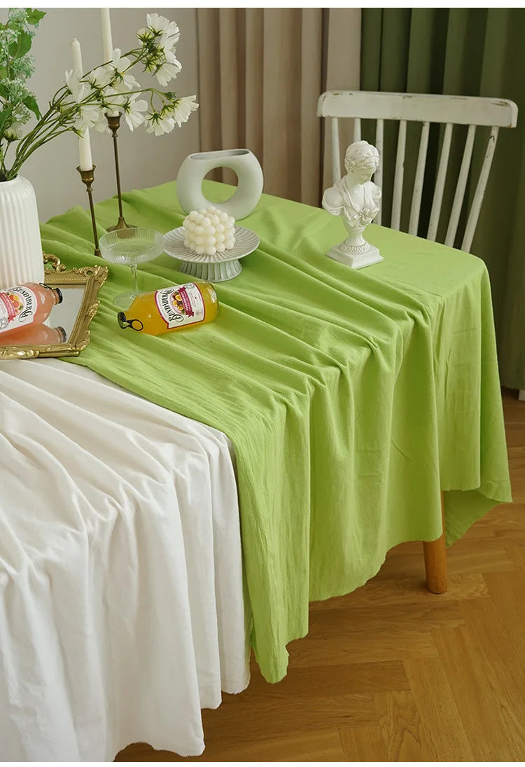 A lime green rectangular tablecloth set for dining or events, featuring white ceramic decor and a vintage-style wooden chair.