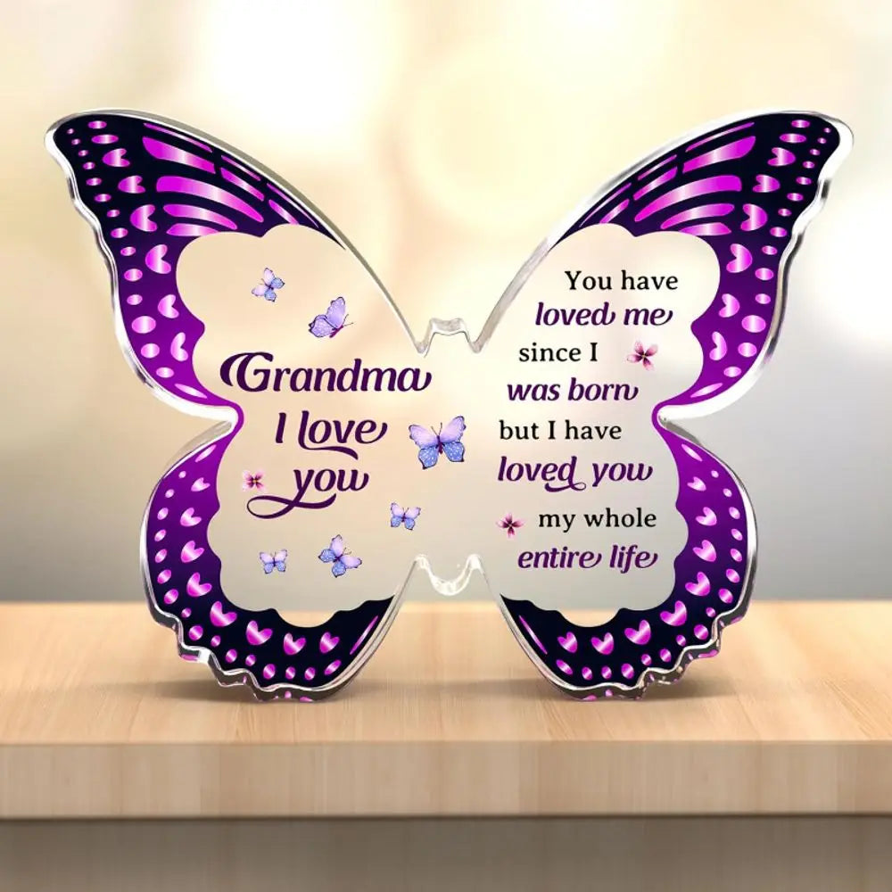 A purple and pink acrylic butterfly keepsake with engraved text that reads Grandma I love you.
