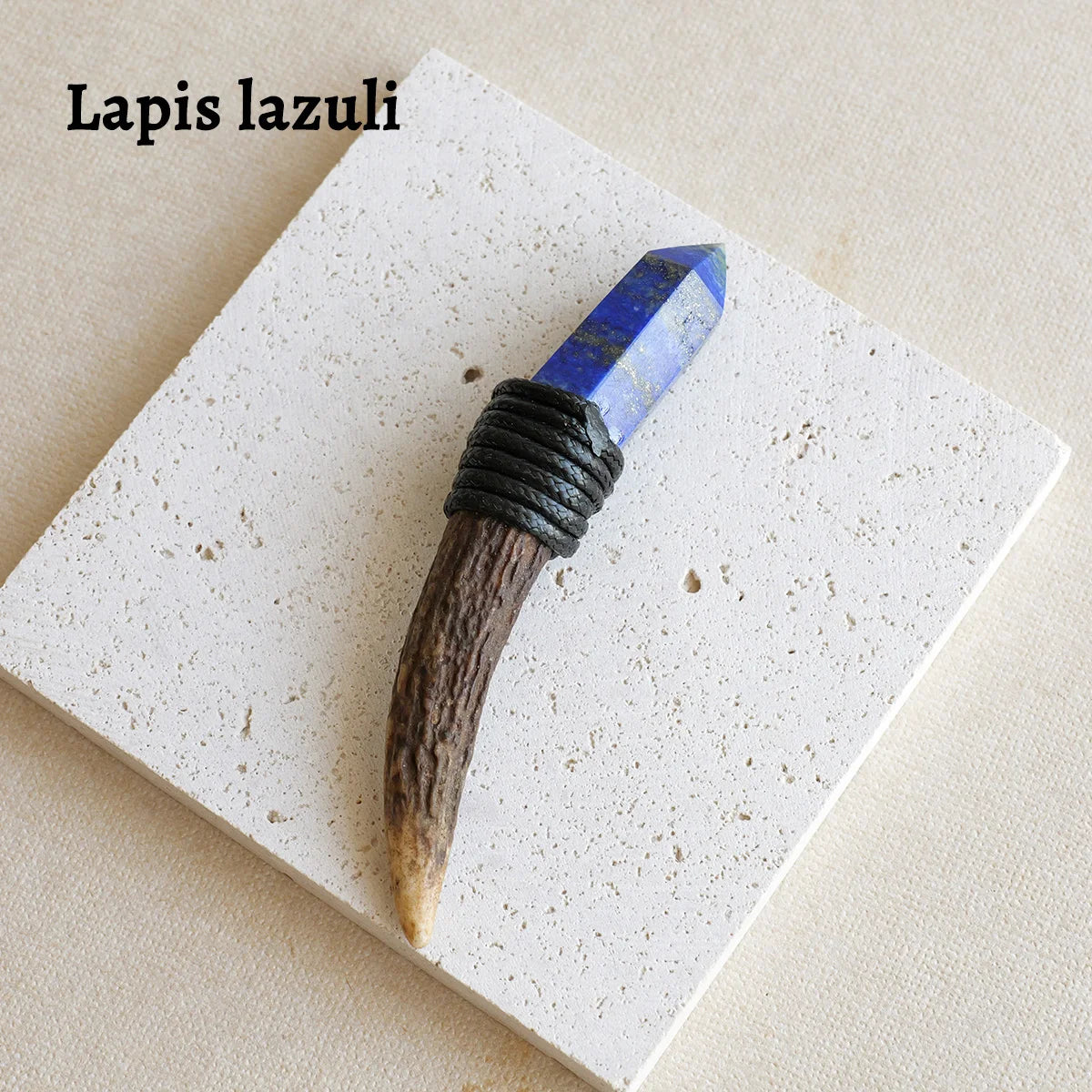 A blue lapis lazuli crystal scepter wand with a dark handle resting on a white square surface.