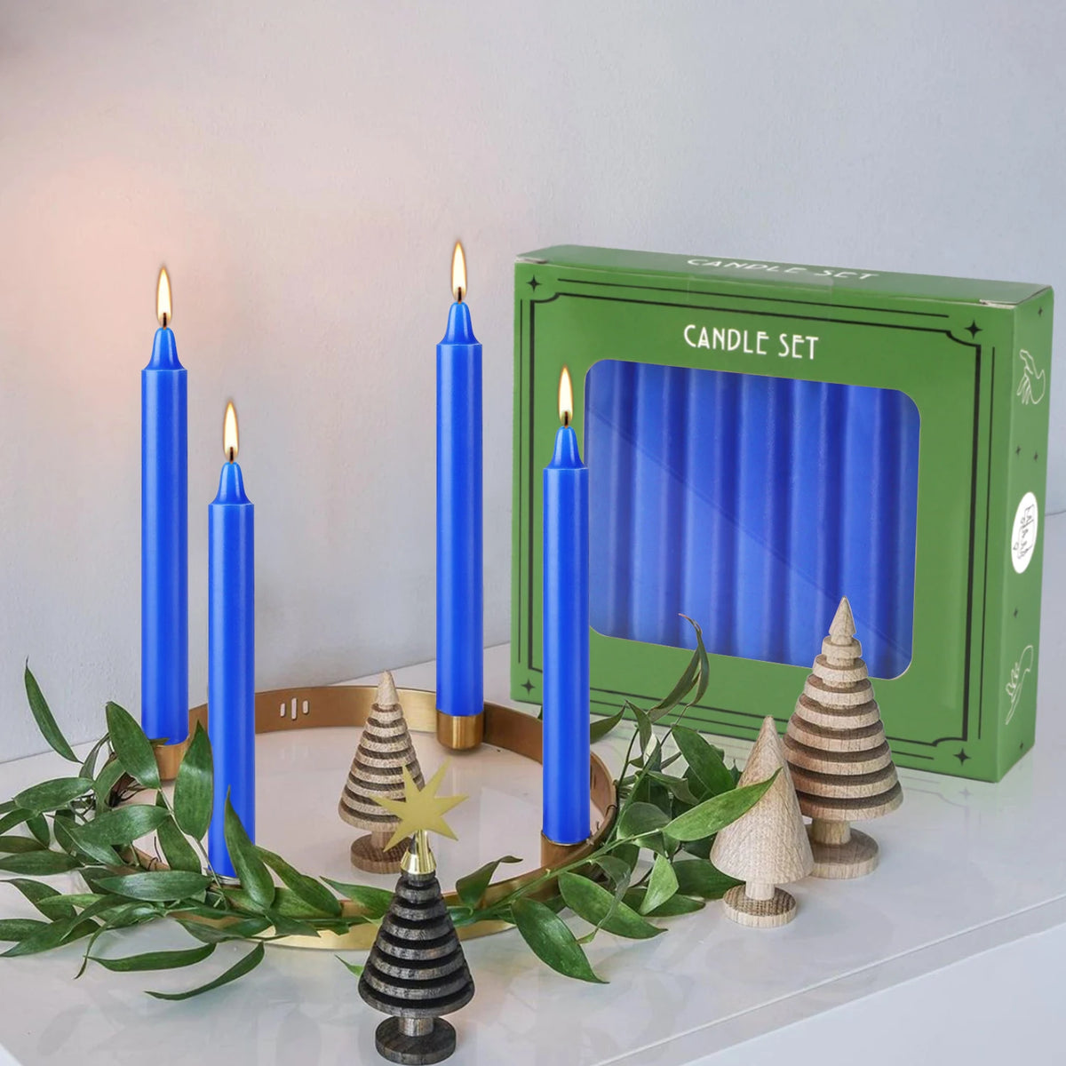 A set of blue stick candles displayed in a green box with decorative pinecone-shaped accents.