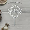 A silver acrylic cake topper with a geometric shape and the words Happy Birthday on a stick.