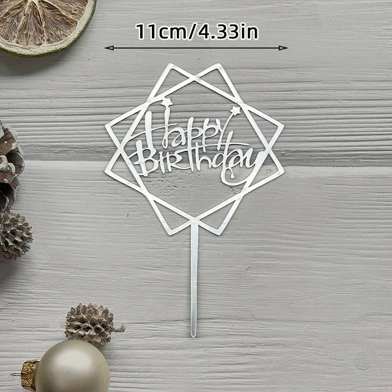 A silver acrylic cake topper with a geometric shape and the words Happy Birthday on a stick.