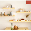 A display of natural wood floating shelves mounted on a light beige wall, featuring various decorative items and books.