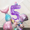 A set of iridescent purple and pink mermaid shell number balloons forming the number five for a party decoration.