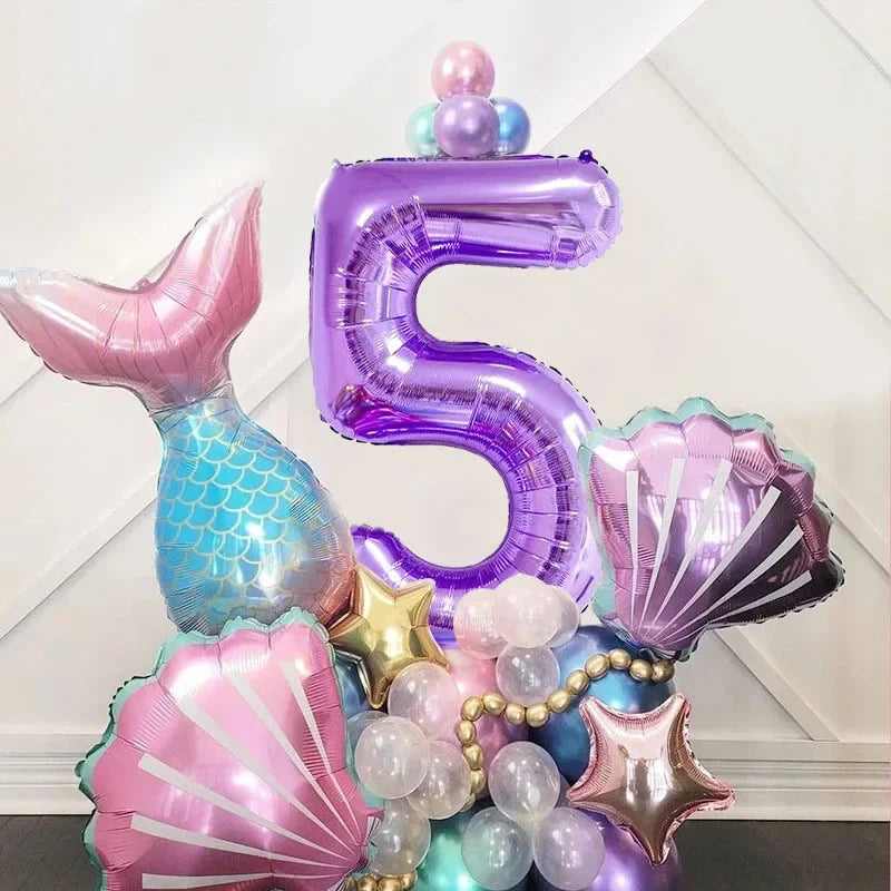 A set of iridescent purple and pink mermaid shell number balloons forming the number five for a party decoration.