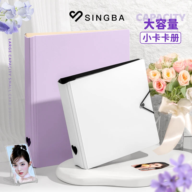 A white A5/A4 ring binder for trading cards and photos displayed next to a purple folder and flowers.