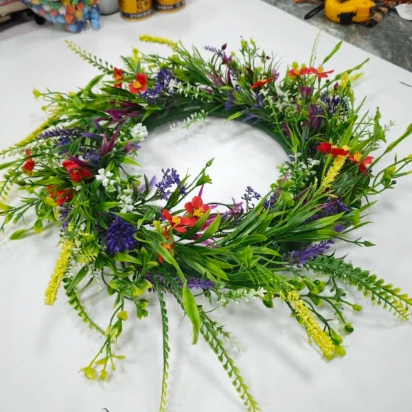 A vibrant artificial wildflower door wreath featuring mixed green, purple, red, and yellow flowers for spring and summer deco
