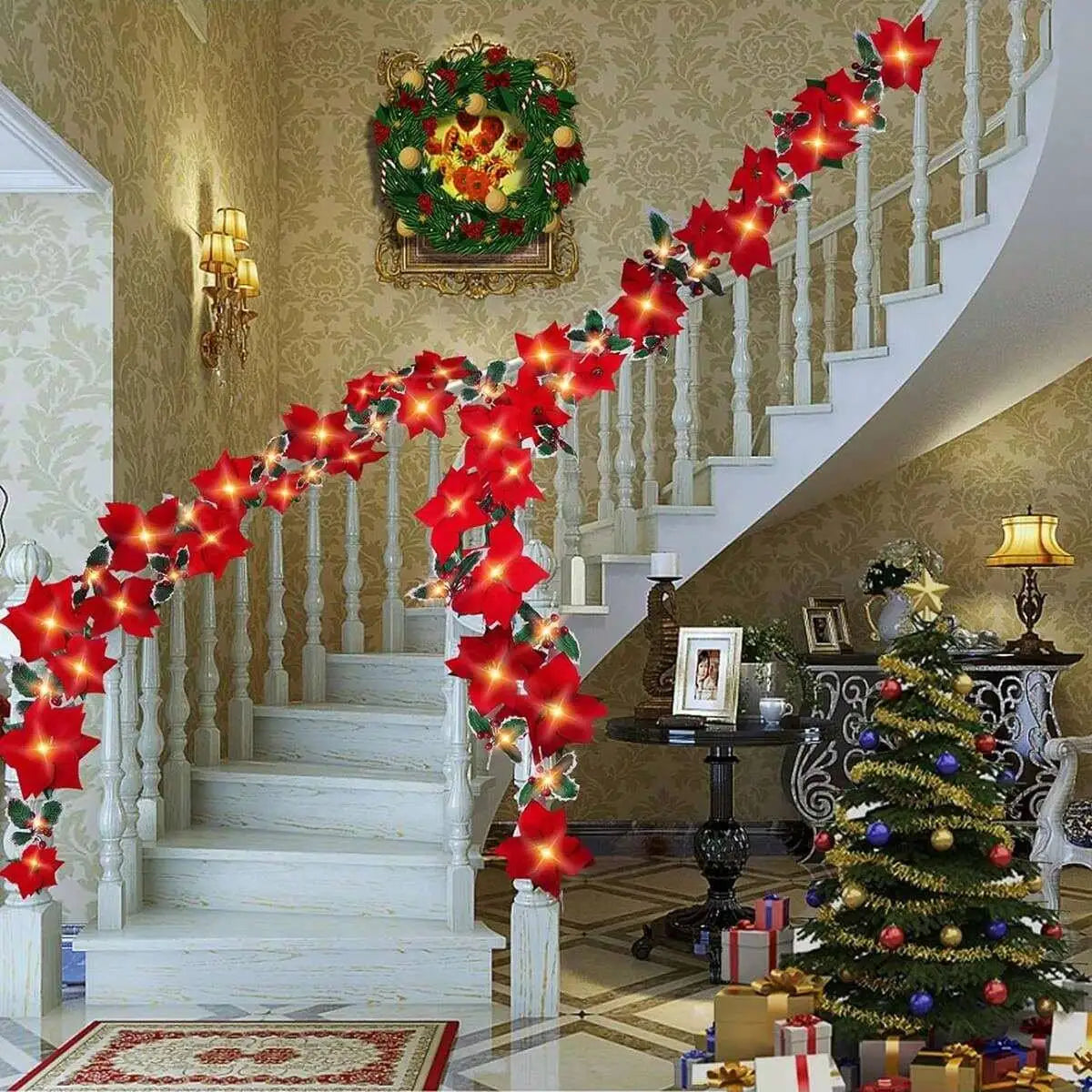A long red poinsettia garland lights decorate a white staircase and interior wall.