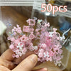 A hand holds a clear plastic package containing 50 pieces of pink and white resin ladybug nail art charms.