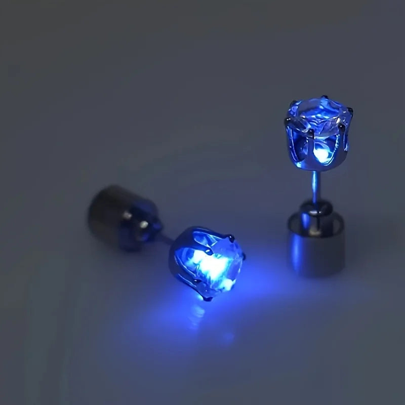 A close-up of a pair of blue LED light-up stud earrings resting on a surface.