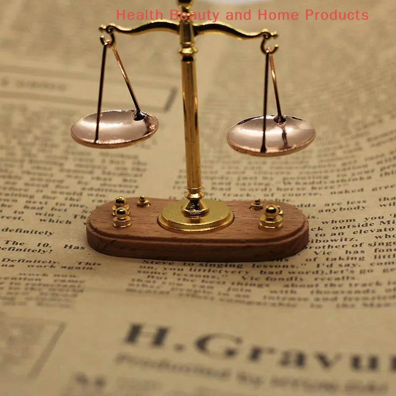 A vintage miniature balance scale with brass arms and wooden base is shown on a piece of paper.