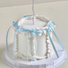 A white cake decorated with ruffled borders and light blue ribbons, used as a birthday decoration.