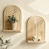 A set of geometric wooden wall shelves with arched grooves displaying a potted plant and a glass candle.