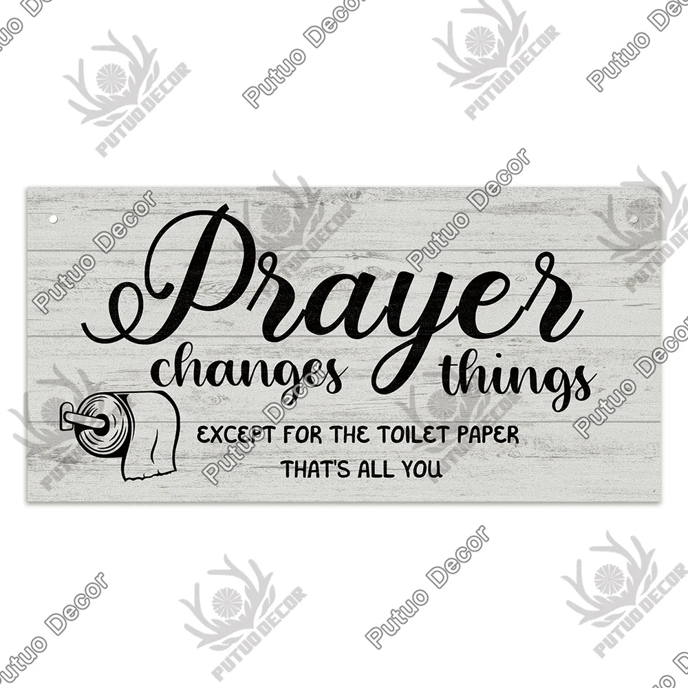 A rustic wooden sign with black script text that reads Prayer changes things except for the toilet paper that's all you