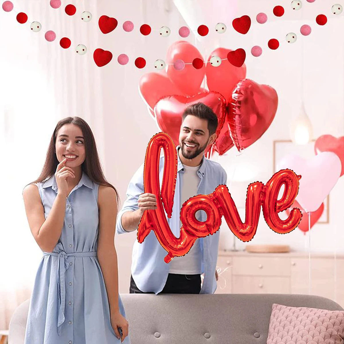 Junges Paar lächelt, umgeben von roten und rosa herzförmigen Ballons für einen romantischen Anlass.