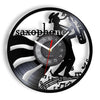 A black wall clock face featuring a silhouette of a saxophone player and musical notes on a vinyl record design.