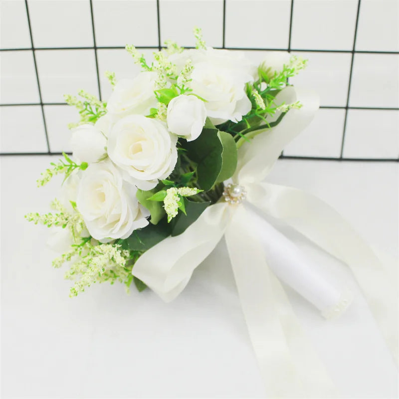 Elegant white silk rose bridal bouquet with green foliage tied with a white ribbon