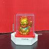 A golden solar-powered waving lucky cat figurine displayed in a clear acrylic box.