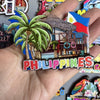 A hand holds a collection of wooden fridge magnets featuring tropical scenes and the word Philippines