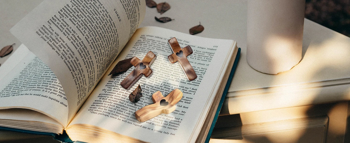 An open book displaying wooden comfort prayer crosses on a page, set on a light surface.