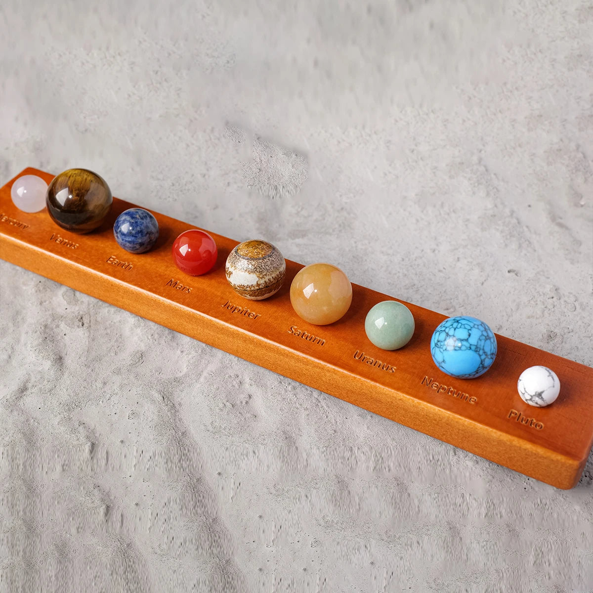 A wooden set of natural crystal solar system planet balls arranged in a row.