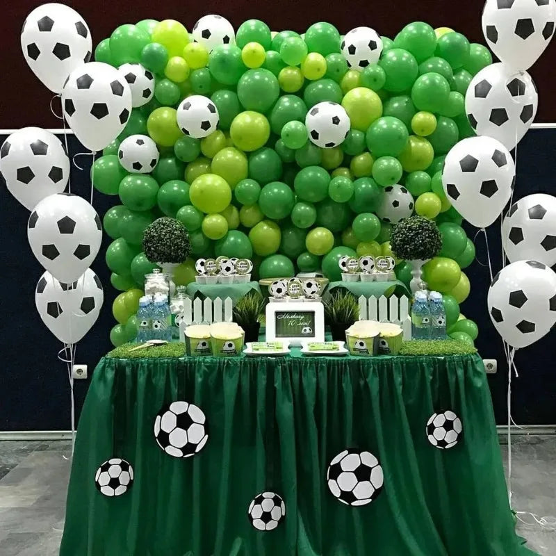 A green balloon wall decorated with white and lime green latex football-shaped balloons on a table.