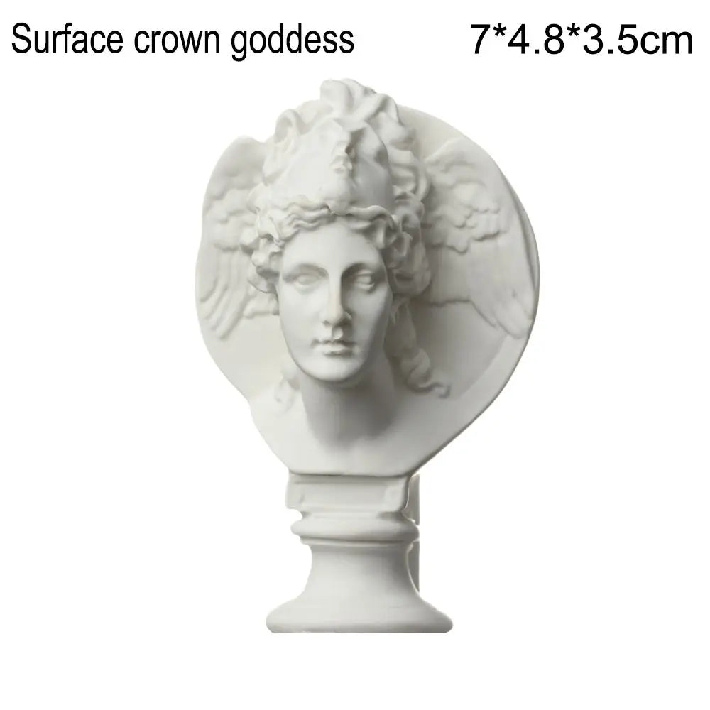 A white plaster bust miniature of a surface crown goddess with flowing hair mounted on a pedestal.