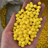A hand holds a large cluster of bright yellow foam beads for crafting and decoration.