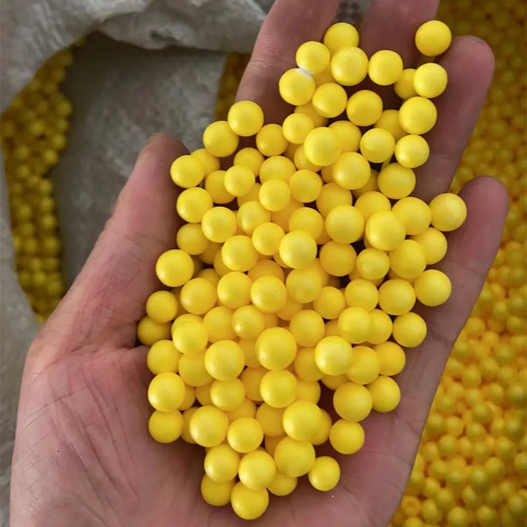 A hand holds a large cluster of bright yellow foam beads for crafting and decoration.