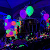 A dark party setting with neon glow-in-the-dark latex balloons in various colors like green, purple, and orange.