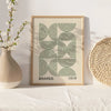 A framed art print featuring concentric circle patterns in olive green on a light wood background.