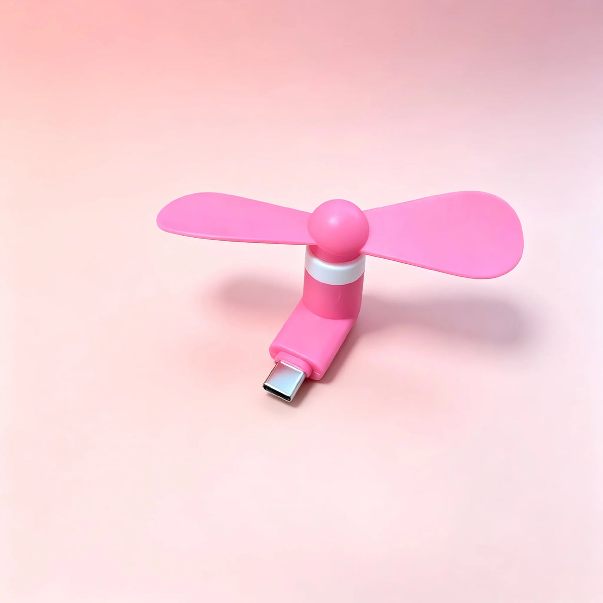 A pink portable USB-C mini fan with soft blades shown against a light pink background.